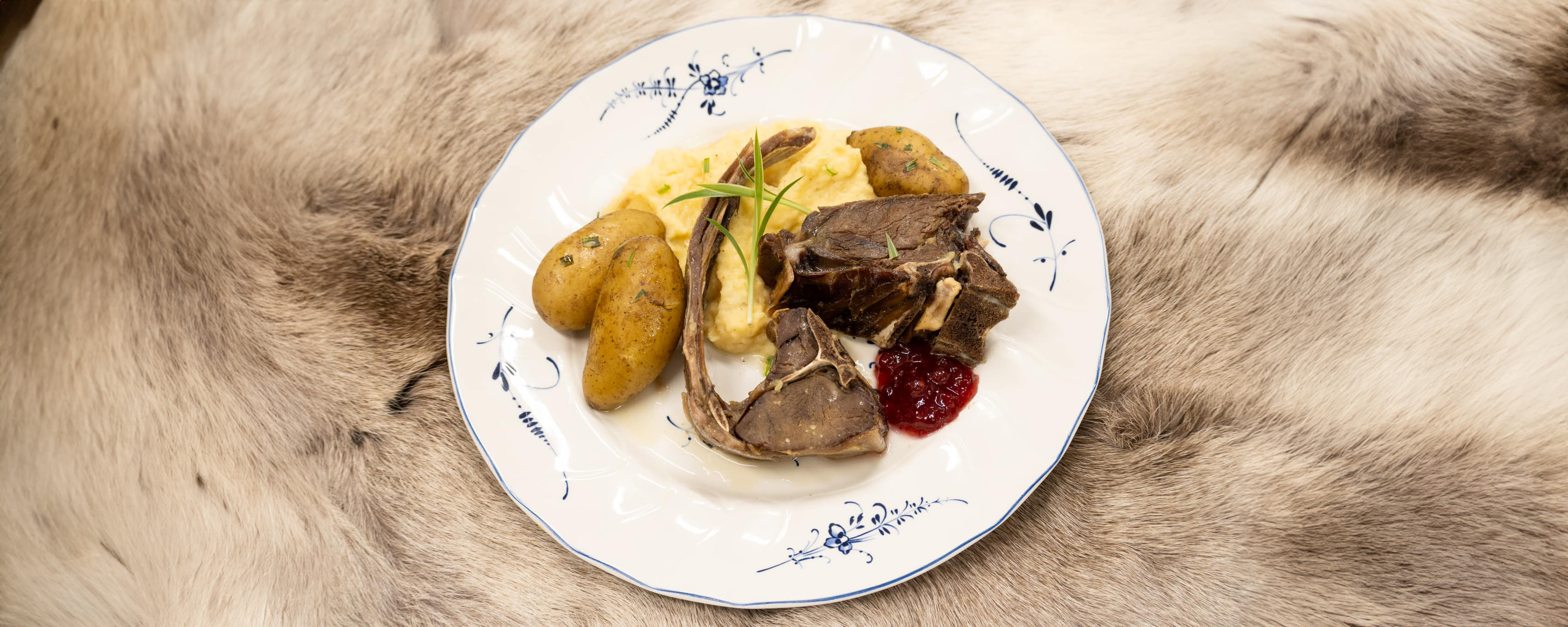 nydeøig pinnekjøtt av reinsdyr fra Raggo Rein, tilberede lekker, ståendes på en reinskinn